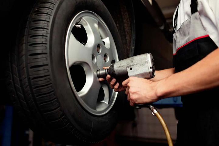 Mains Seulement. Mécanicien Tenant Un Pneu Au Garage De Réparation.  Remplacement Des Pneus D'hiver Et D'été